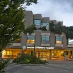 Seattle Children’s Hospital building with greenery and the Giraffe Entrance sign visible.