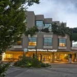 Seattle Children’s Hospital building with greenery and the Giraffe Entrance sign visible.