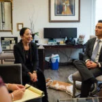 "People in a professional office having a meeting, with a dog lying on the floor"