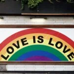 "Rainbow mural with the words 'Love is Love' painted on a wall"