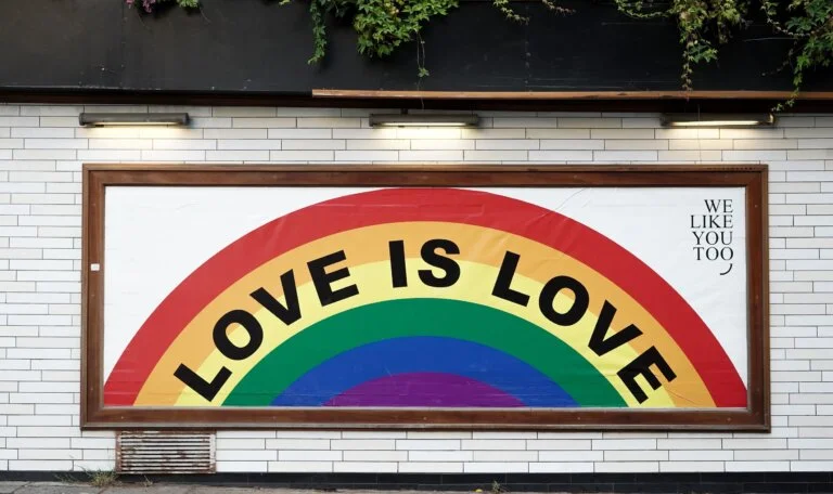 "Rainbow mural with the words 'Love is Love' painted on a wall"