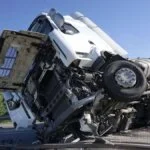 "Overturned semi-truck with severe front-end damage on a highway"