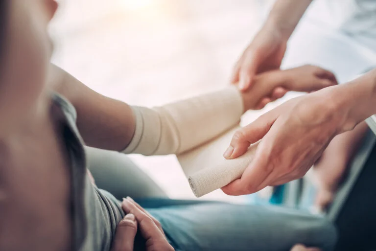 Doctor using bandage for hand injury.