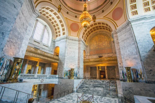 The ornate marble interior of a grand building with a domed ceiling and a grand staircase.