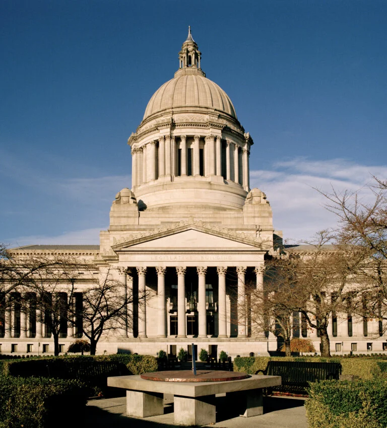 A large government building with a domed roof and columns on a sunny day.
