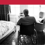 "Elderly man in wheelchair facing window in a quiet bedroom"