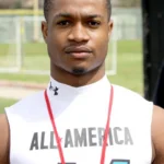 "Football player in All-America gear posing outdoors at a training facility"