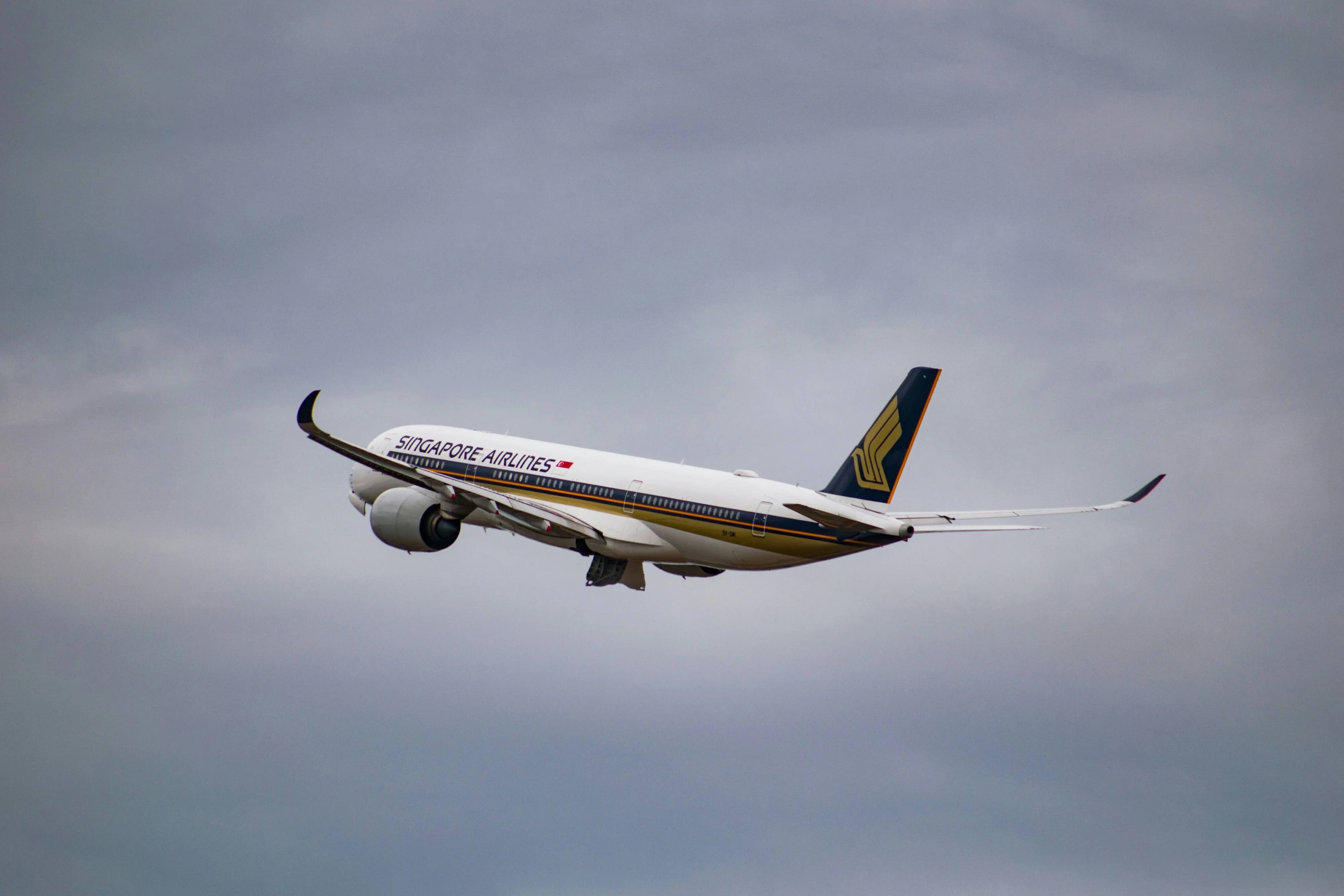 A Singapore Airlines passenger jet in flight, climbing through a cloudy sky.