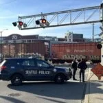 This image shows a railroad crossing in Seattle where a freight train is passing through.