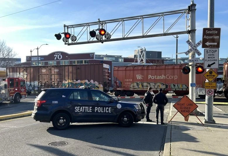 This image shows a railroad crossing in Seattle where a freight train is passing through.