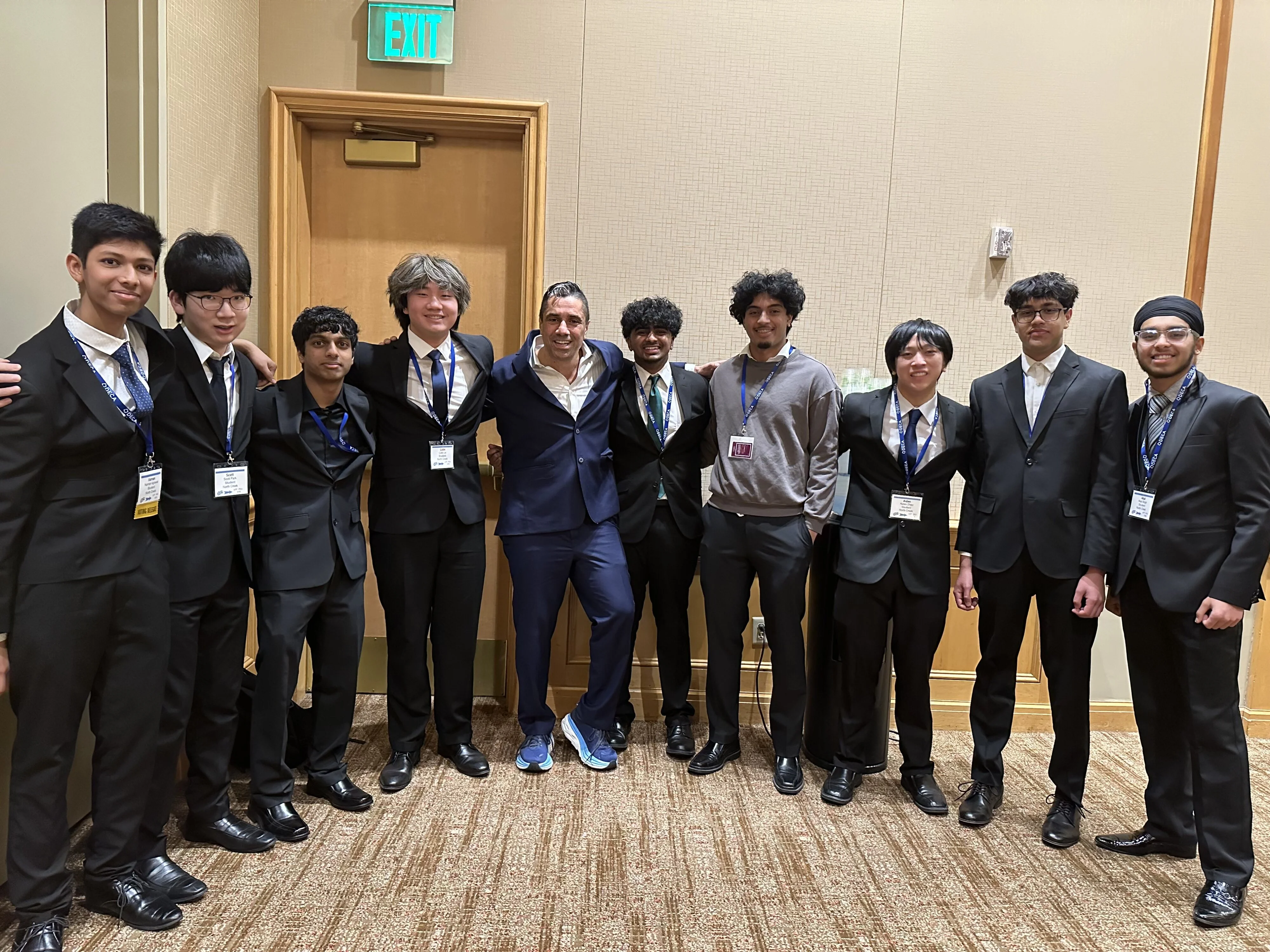 "Group photo of students in suits with speaker at a conference event."