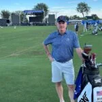Brad Moore stands on the fairway at The American Express golf event next to a PXG golf bag with his name