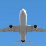 Underside view of a commercial airplane in flight against a clear blue sky