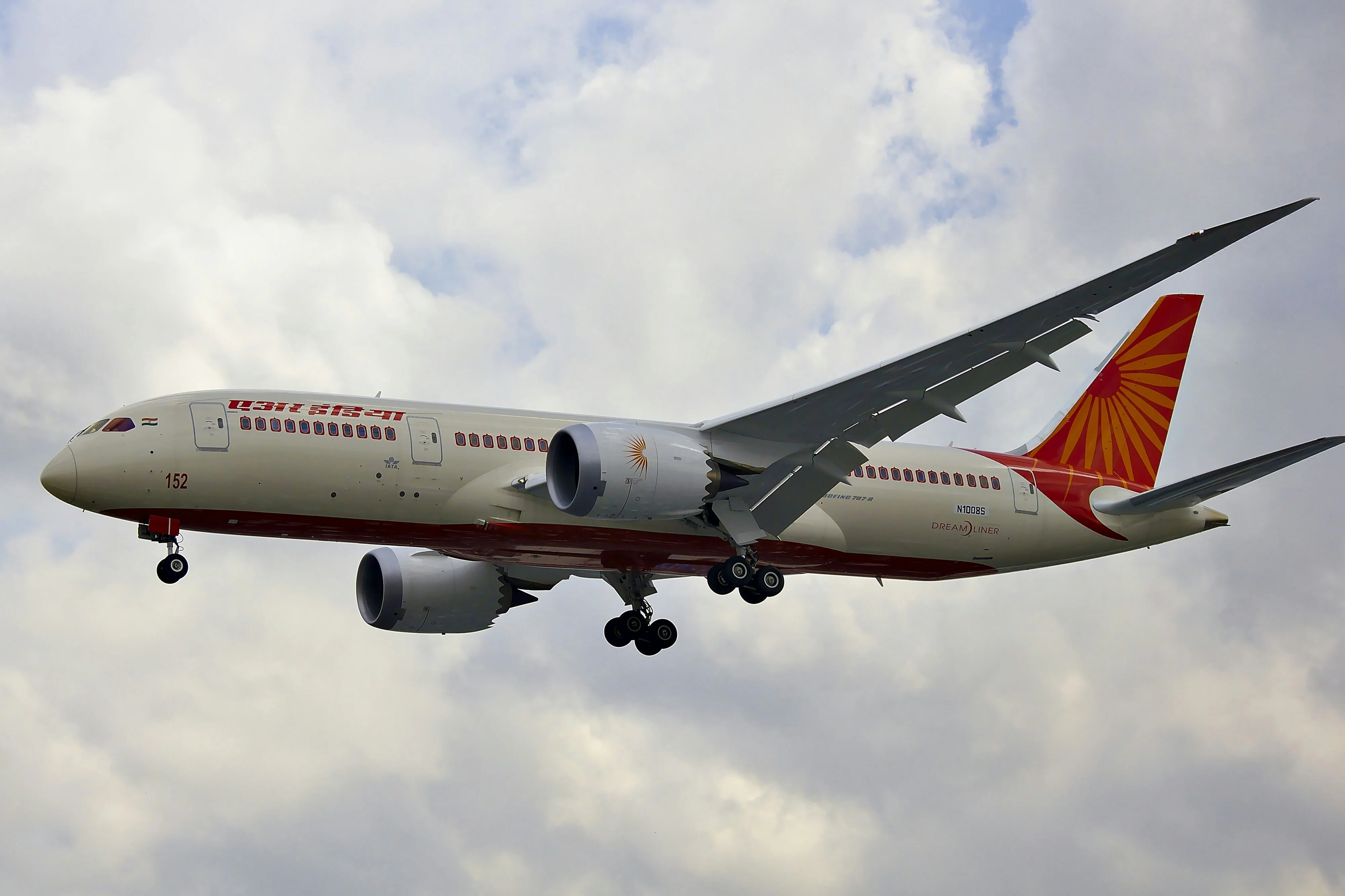 Air India Boeing 787 Dreamliner in flight with landing gear extended under a cloudy sky