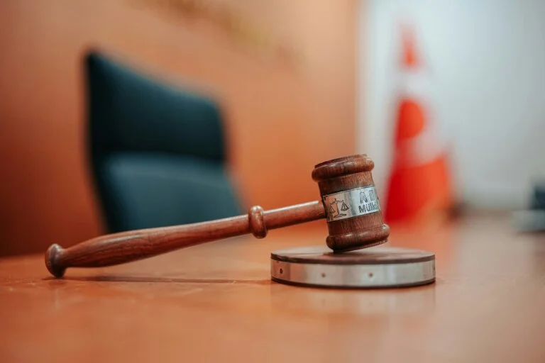 Close-up of a judge’s gavel resting on a sound block in a courtroom.