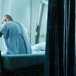 Male patient sitting in hospital bed.