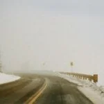 Snowy mountain road with limited visibility and missing guardrail coverage illustrating dangerous conditions caused by systemic failures in public safety