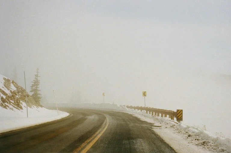 Snowy mountain road with limited visibility and missing guardrail coverage illustrating dangerous conditions caused by systemic failures in public safety